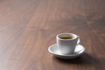 Fresh espresso in a white cup on walnut table with copy space