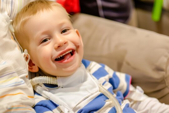 A young boy with a tracheostomy tube smiles brightly while sitting on a couch, radiating pure joy and infectious happiness.