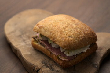 Roast beef and mozzarella sandwich with ciabatta bun on olive board