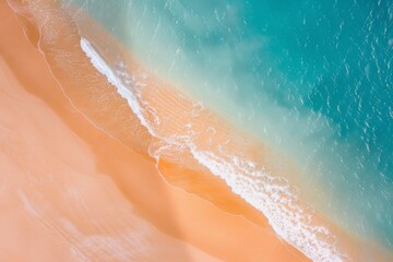 An aerial view of a sandy beach with clear turquoise waters and white foamy waves lapping the shore.