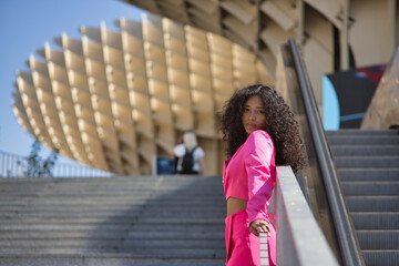Woman, young, beautiful, Latina, brunette with curly hair, wearing a pink jacket suit, with a...