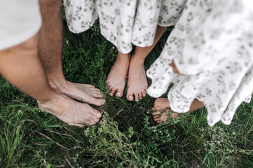 Barefoot man, woman and child girl, happy healthy family standing on the grass in a field. Close up photo of feet close up of dad, mom, daughter, lifestyle, love concept.