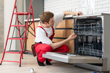 Concept maintenance service of home appliances. Worker cleans filter in the dishwasher. Male repairman checking food residue filters