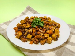 Oseng Tempe and Tofu is Indonesian stir-fried tempeh, tofu and carrot seasoned with shallots, garlic, salt, bay leaf, galangal and sweet soy sauce served on white plate