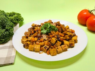 Oseng Tempe and Tofu is Indonesian stir-fried tempeh, tofu and carrot seasoned with shallots, garlic, salt, bay leaf, galangal and sweet soy sauce served on white plate