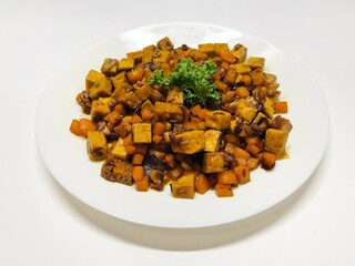 Oseng Tempe and Tofu is Indonesian stir-fried tempeh, tofu and carrot seasoned with shallots, garlic, salt, bay leaf, galangal and sweet soy sauce served on white plate