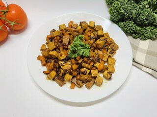 Oseng Tempe and Tofu is Indonesian stir-fried tempeh, tofu and carrot seasoned with shallots, garlic, salt, bay leaf, galangal and sweet soy sauce served on white plate
