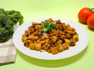 Oseng Tempe and Tofu is Indonesian stir-fried tempeh, tofu and carrot seasoned with shallots, garlic, salt, bay leaf, galangal and sweet soy sauce served on white plate
