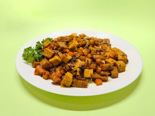 Oseng Tempe and Tofu is Indonesian stir-fried tempeh, tofu and carrot seasoned with shallots, garlic, salt, bay leaf, galangal and sweet soy sauce served on white plate