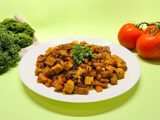 Oseng Tempe and Tofu is Indonesian stir-fried tempeh, tofu and carrot seasoned with shallots, garlic, salt, bay leaf, galangal and sweet soy sauce served on white plate