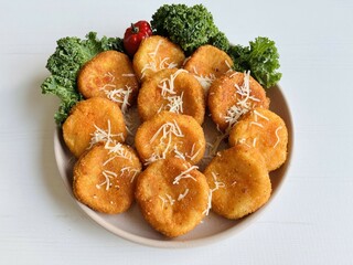 Home made potato croquettes - mashed potatoes balls with grated mozzarella cheese seasoned with spices; breaded and deep fried in olive oil served with cheese garnish