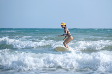 Asian surfing woman riding the waves on sunny day, outdoor activities, water sports activities concept