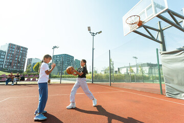 Concept of sports, hobbies and healthy lifestyle. Young people playing basketball on playground outdoors