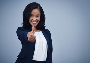 Happy woman, portrait and feedback with thumbs up for winning, good job or success on a blue studio background. Female person or employee with smile, like emoji or yes sign for well done on mockup