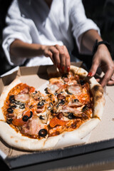 A woman in a bathrobe eats pizza on a balcony overlooking the mountains. Hotel holiday concept. Pizza