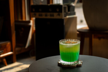 tropical brazilian mocktail with pineapple, green apple, and orange soda in a transparent glass. Served on black table in a vintage music room environment