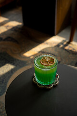 tropical brazilian mocktail with pineapple, green apple, and orange soda in a transparent glass. Served on black table in a vintage music room environment