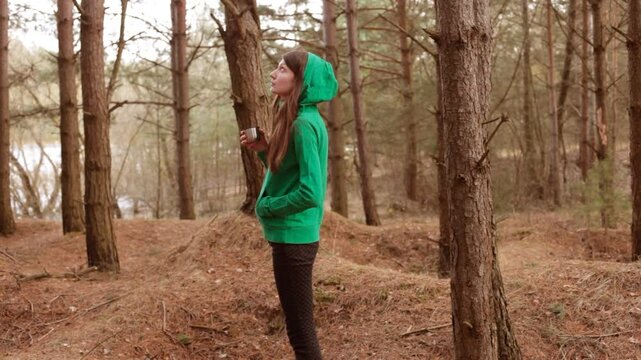 Woman in a hood enjoying the silence in the forest. 