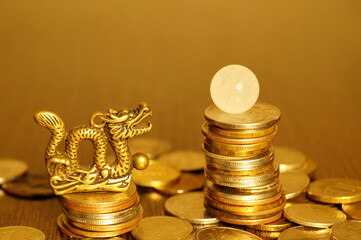 A dragon statuette with coins and a quartz ball on the table.