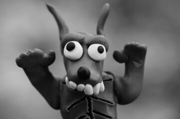 A figure of a funny werewolf made of plasticine. Black and white background.