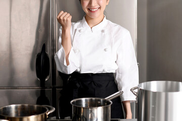 調理場でガッツポーズをする若い女性調理師