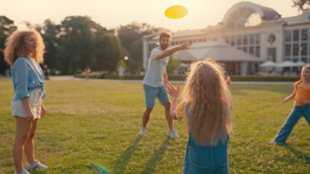 A happy family is spending quality time together, playing frisbee in a beautiful park under the sunny sky, enjoying the outdoors and each others company
