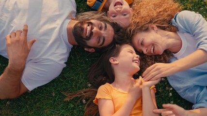 On a sunny day, a happy family lies on the grass, laughing and bonding together, capturing a special moment of joy and togetherness, filled with love and care - Powered by Adobe