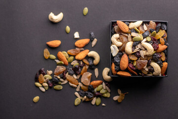 Mix dry fruits in a square bowl on a dark grey background