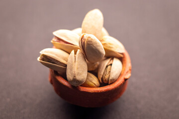 Pistachio nuts in wooden bowl on black background. Pistachios are rich in nutrients and good source of protein, fiber, and antioxidants. Healthy food concept. Flat layout.