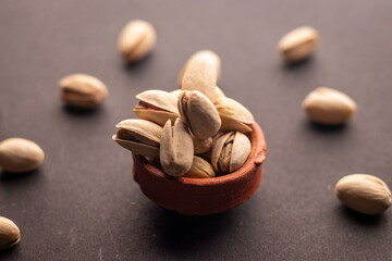 Pistachio nuts in wooden bowl on black background. Pistachios are rich in nutrients and good source of protein, fiber, and antioxidants. Healthy food concept. Flat layout.