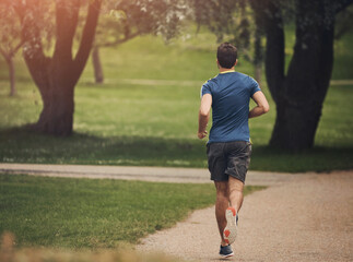Running, back and man in park for fitness, cardio and exercise on pathway. Male athlete, jogging...