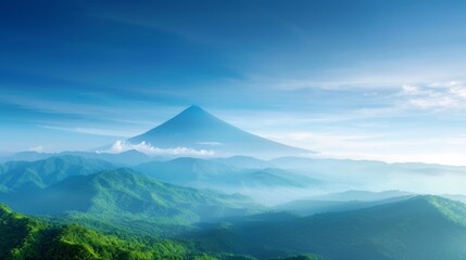 Fototapeta premium A stunning view of a mountain peak surrounded by mist and lush green hills under a clear blue sky. Perfect for nature landscapes.