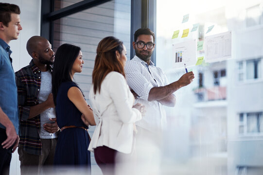 Business, people and communication with glass in office for campaign management, collaboration and work. Sales directors, conversation and graphs for revenue, development and income growth or review.