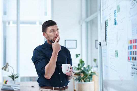 Man, thinking and coffee in office for brainstorming with whiteboard, thoughts and planning for day ahead or designer tasks. Project manager, ideas and strategy for campaign schedule and goal setting