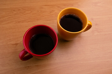 View from above of coffee cups on wooden background. Yellow mug. red cup
