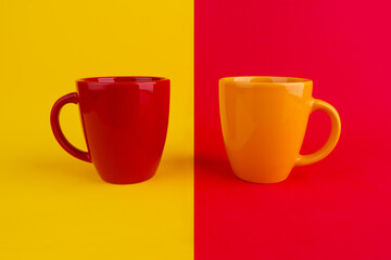 Cups of coffee or tea on yellow and red two-color background. Yellow mug. Red mug. Corporate colors. ceramic mugs