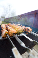 Meat Skewers Grilling Over Charcoal. Close-up shot of meat skewers grilling over charcoal on a portable grill outdoors.