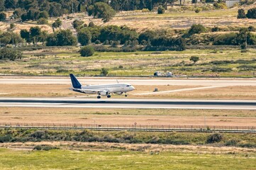 Fototapeta premium Commercial airplane with a white fuselage and dark blue tail landing on the runway.