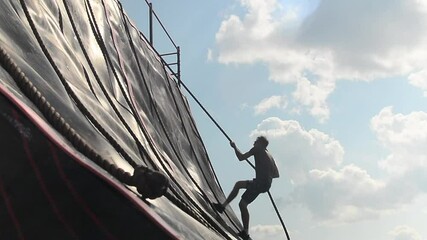 obstacle course young man rises using a rope. - Powered by Adobe