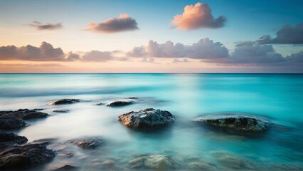 Naklejka premium A serene seascape with smooth water and large rocks under a cloudy sky