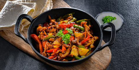 Fajita with peppers and onions served on a hot iron skillet