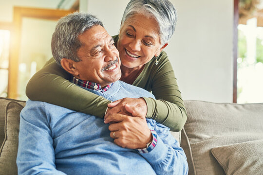 Happy, hug and elderly couple on sofa for love, wellness and pleased for successful retirement. Senior woman, man and smile at home for life insurance, financial security and good news in marriage - Powered by Adobe