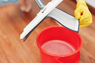 Woman mopping wooden floor with buckets of water nearby