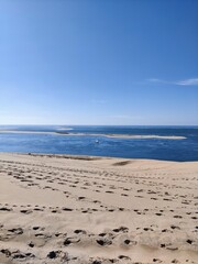 Sailboat in the distant seen from a sand dune with footsteps