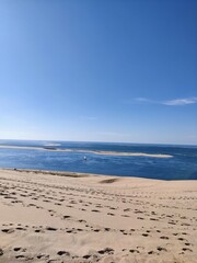 Sailboat in the distant seen from a sand dune with footsteps