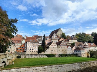 Fototapeta premium Cityscape of a swabian city in south germany with green grass, a river, cloudy sky and half-timbered houses