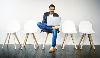 Fototapeta premium Waiting room, business man and laptop for interview, planning and research questions for hr recruitment. Wall background, male candidate and digital for information, opportunity and reading portfolio