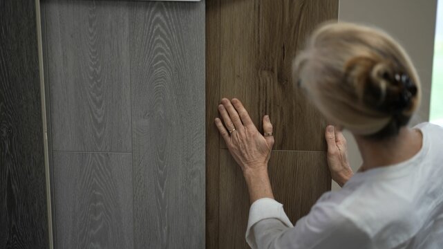 Running hand across lvp, luxury vinyl plank wood samples in a floor store for a home remodeling project.