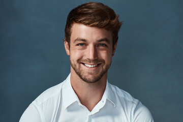 Obraz premium Portrait, business and man with smile, studio and happy for internship in bank for bookkeeper and mockup. Blue background, professional and clothes for accountant, cheerful and confidence of employee