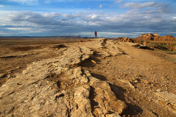 Under a beautiful cloudy October sky, a female silhouette punctuates a panoramic view of a splendid geological landscape in the Bardenas Reales (Spanish Navarre)